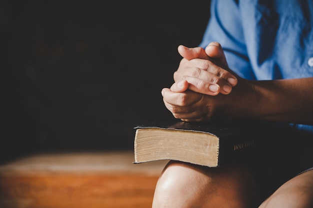 Spirituality and religion, Hands folded in prayer on a Holy Bible in church concept for faith.