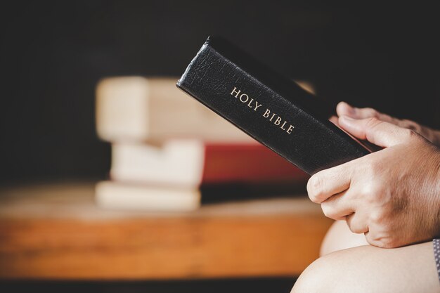 Spirituality and religion, Hands folded in prayer on a Holy Bible in church concept for faith.