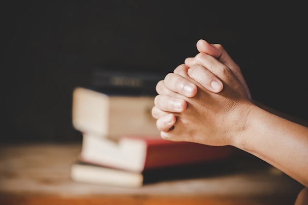 Spirituality and religion, hands folded in prayer on a holy bible in church concept for faith.