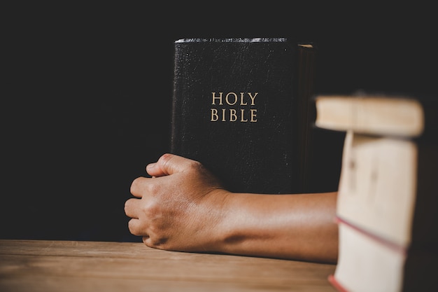 Spirituality and religion, Hands folded in prayer on a Holy Bible in church concept for faith.