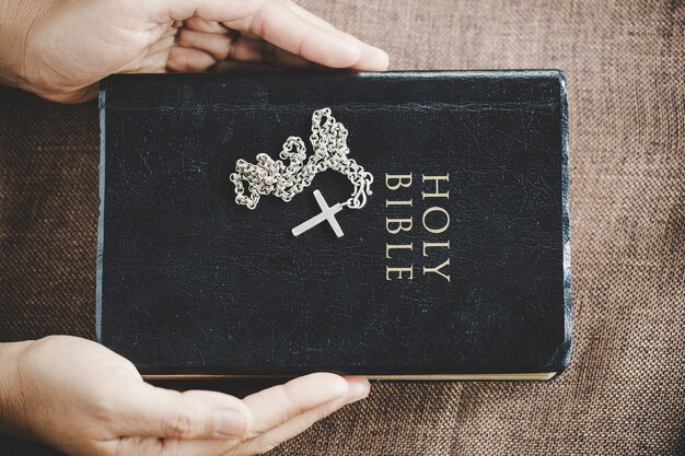 Spirituality and religion, Hands folded in prayer on a Holy Bible in church concept for faith.