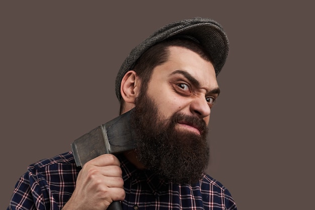 Free photo spiteful brutal bearded man shave by axe. portrait of hipster with beard. hot-tempered male concept. crazy emotion on face.