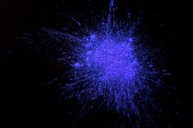 Splash of dark blue holi color on black surface