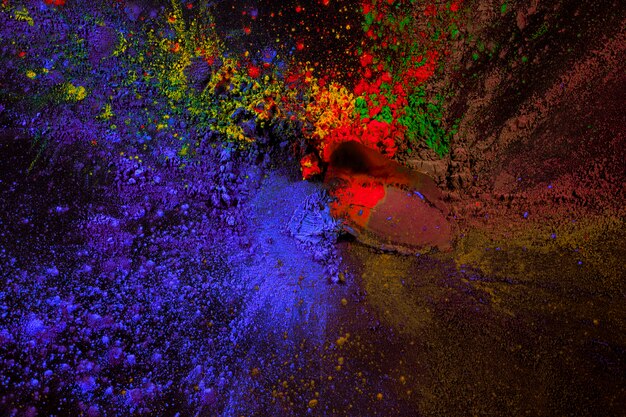 Splatter of holi color powder over black surface