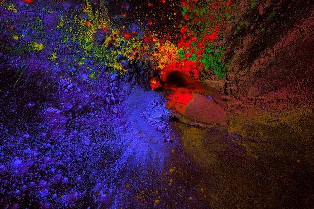 Splatter of holi color powder over black surface