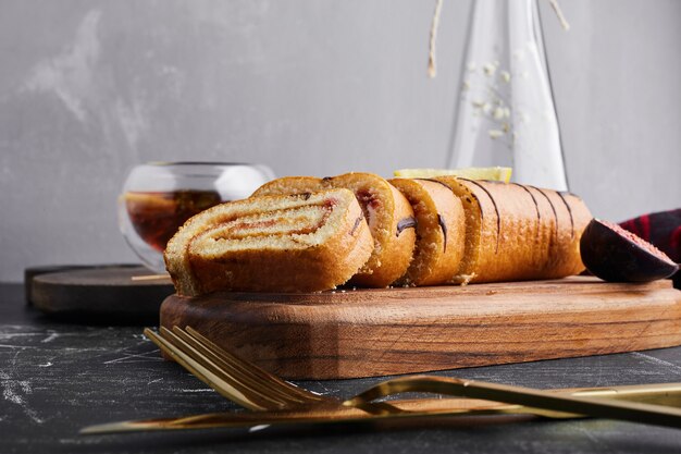 Sponge rollcake with chocolate filling on a wooden board . 