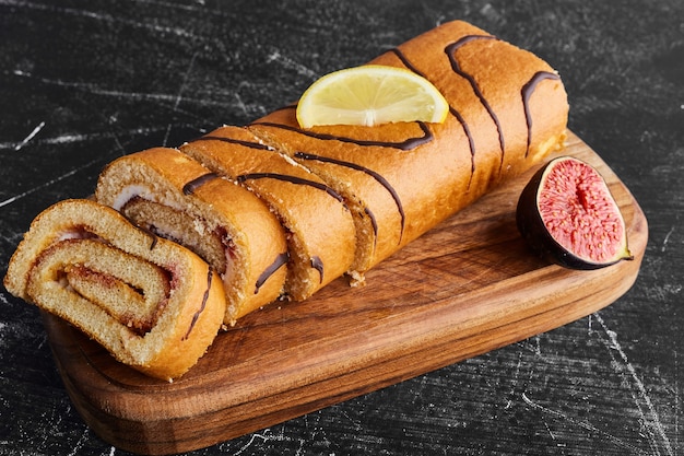 Sponge rollcake with chocolate filling on a wooden board. 