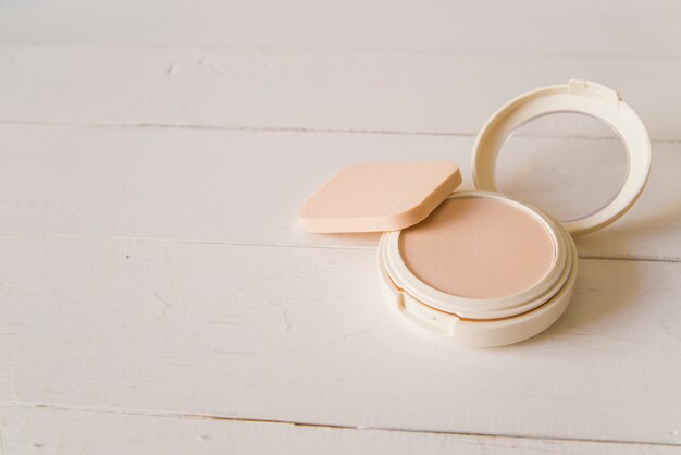 Sponge with compact face powder on beige backdrop