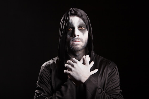 Free photo spooky angel of death over black background with a hood. halloween outfit.