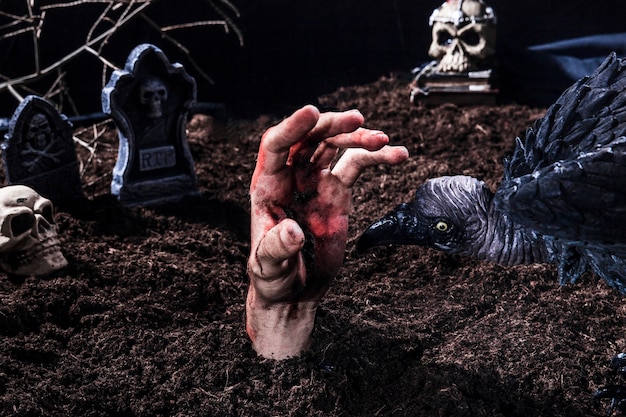 Призрачная птица пытается укусить руку зомби на кладбище Хэллоуина