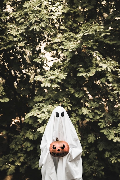 spooky holding pumpkin near bush 