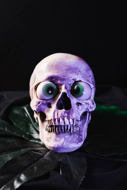 Free photo spooky skull with fancy eyeballs illuminated by purple light