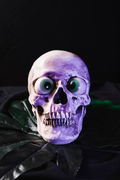 Spooky skull with fancy eyeballs illuminated by purple light