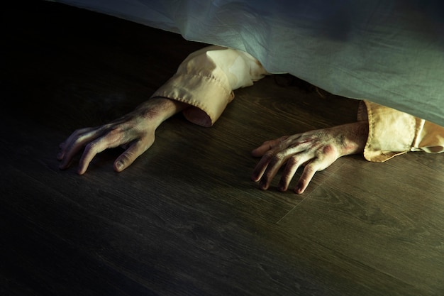 Spooky zombie hands under the bed