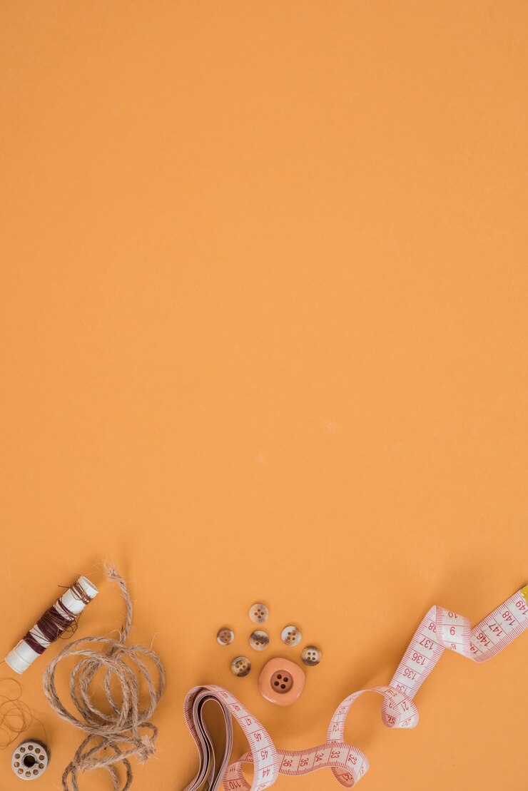 Free Photo spool; jute string; button and measuring tape on an orange background