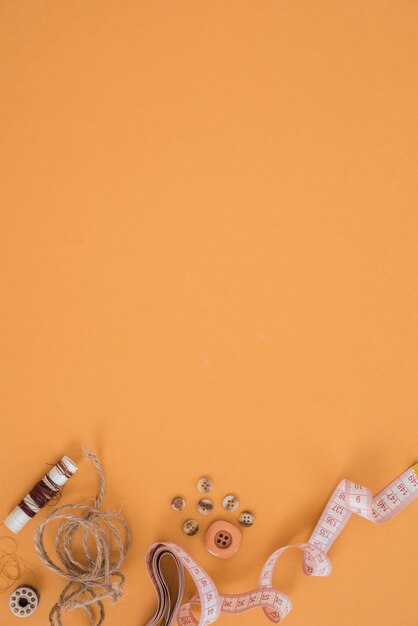 Spool; jute string; button and measuring tape on an orange background