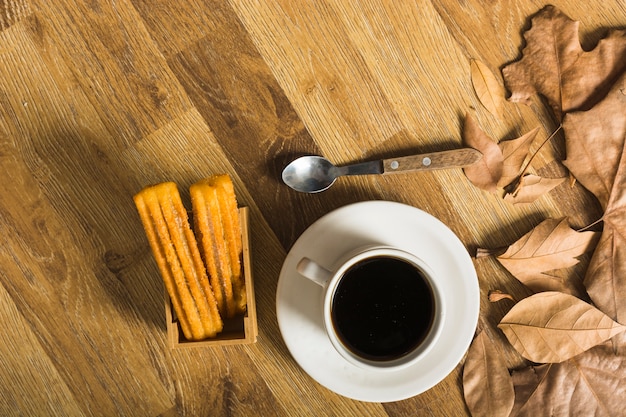 Spoon and leaves near coffee and pastry