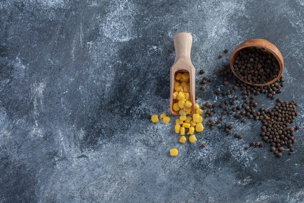 Spoon of sweet corns and grain peppers on marble.
