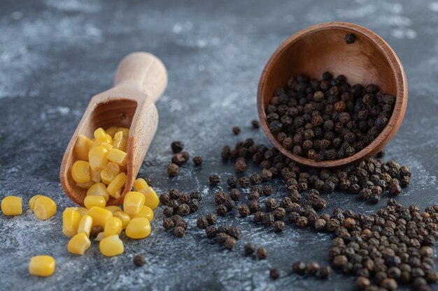 Spoon of sweet corns and grain peppers on marble.