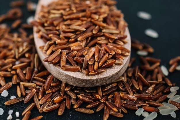 Spoon with brown rice on spilled grains