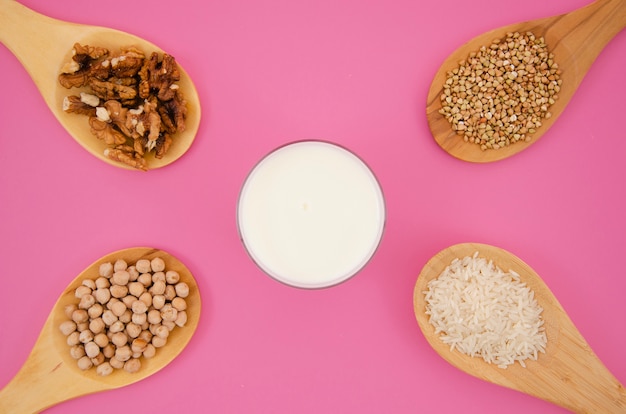 Spoon with cereals and nuts on pink background 