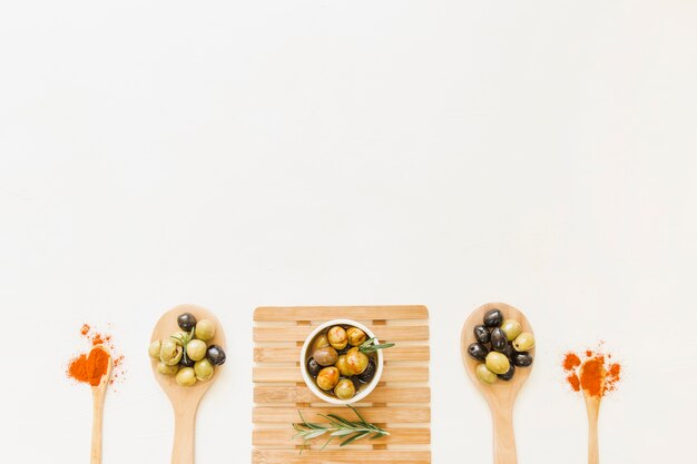 Spoons and plate with olives and spices 