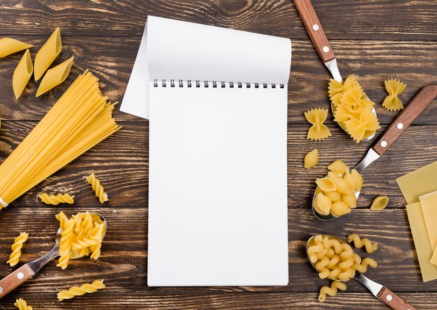 Spoons with pasta beside notebook