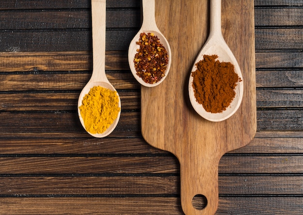 Spoons with spices and cutting board on table
