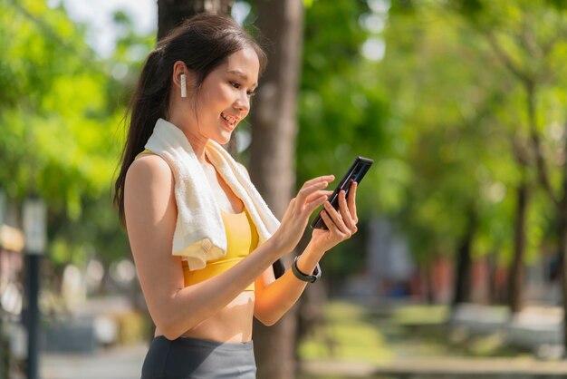 스포츠 활동적인 아시아 여성 스포츠 천은 스마트폰 재생을 설정하여 일상적인 운동 아침에 건강한 생활 방식을 준비합니다.