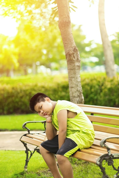 Sport concept little sport runner boy sit on the track and take a deep breath feel tired and bored