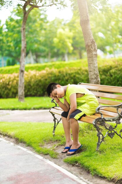 스포츠 컨셉의 작은 스포츠 러너 소년은 트랙에 앉아 심호흡을 하며 피곤하고 지루함을 느낍니다.