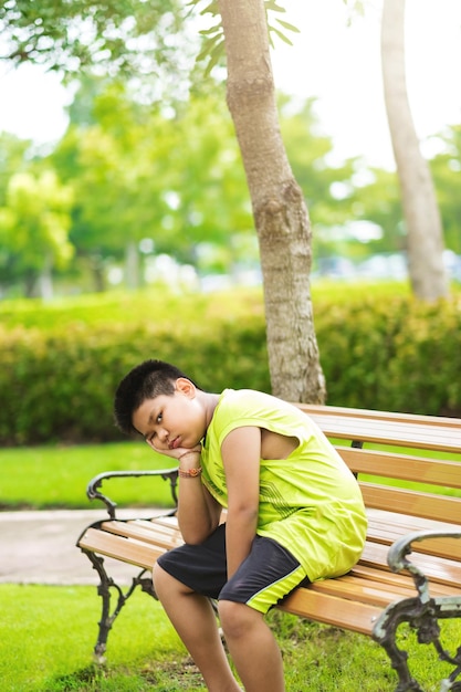 Sport concept little sport runner boy sit on the track and take a deep breath feel tired and bored