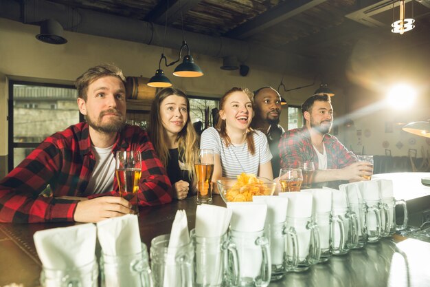 Sport fans cheering at bar, pub and drinking beer while championship, competition is going