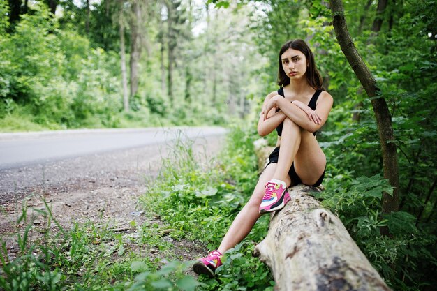 自然でトレーニングした後、緑豊かな公園で休むスポーツウェアのスポーツの女の子健康的なライフスタイル