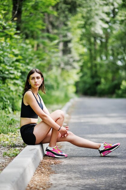 自然でトレーニングした後、緑豊かな公園で休むスポーツウェアのスポーツの女の子健康的なライフスタイル