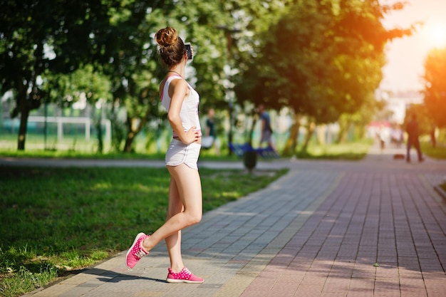 公園で自分撮りをする白いパンツとシャツを着たスポーツの女の子