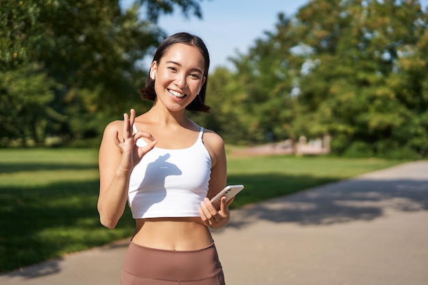 Sport people happy asian girl sportswoman showing okay sign and smiling workout in gym say yes appro