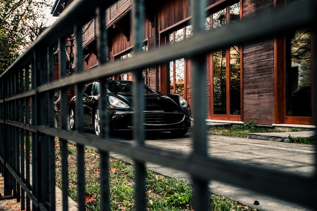 Спортивный седан, черный цвет, стоящий перед зданием, вид спереди через отсюда.