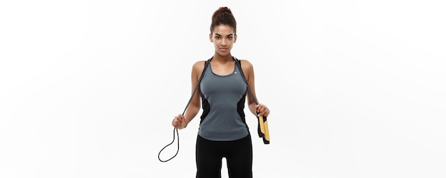 Free photo sport training lifestyle and fitness concept portrait of beautiful happy african american woman exercising with jumping rope isolated on white studio background