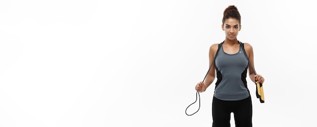 Free photo sport training lifestyle and fitness concept portrait of beautiful happy african american woman exercising with jumping rope isolated on white studio background