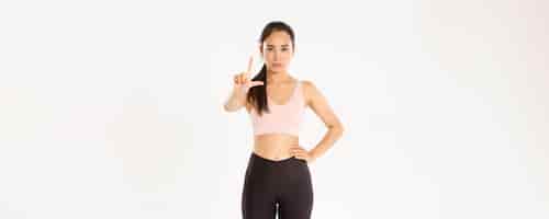 Free photo sport wellbeing and active lifestyle concept serious displeased asian female fitness instructor spor