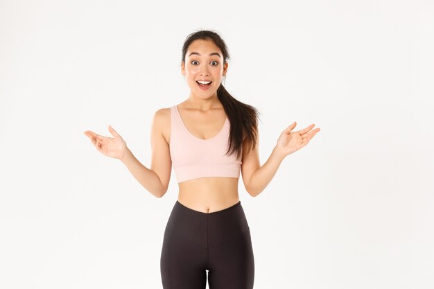 Sport, wellbeing and active lifestyle concept. Surprised and excited asian sportswoman hear about great discounts for workout equipment, gym membership, fitness girl looking amazed