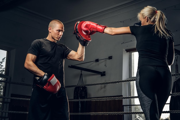 無料写真 陽気なブロンドの女性は彼女の経験豊富なトレーナーとボクシングトレーニングをしています。