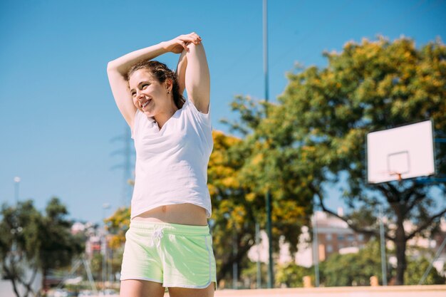 Sportive delighted female teenager warming up outdoors