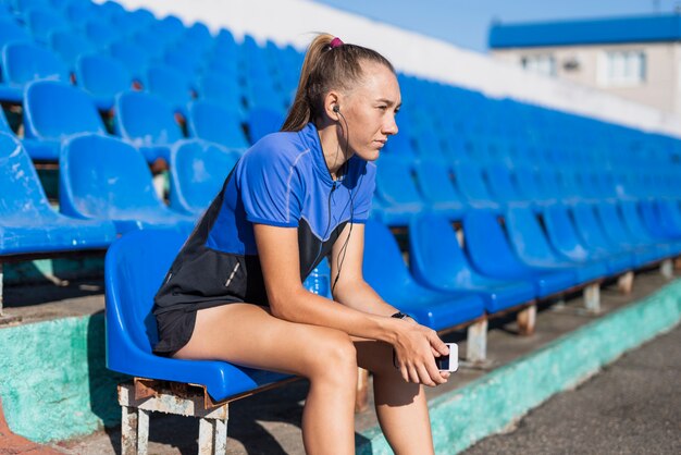 Спортивная женщина на стадионе сидит