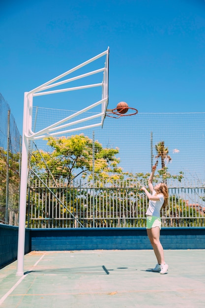 자연 배경에 농구 대에 공을 던지는 낚시를 좋아하는 여성