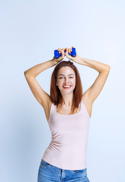 Sportive girl training with one dumbbell or promoting the product. 