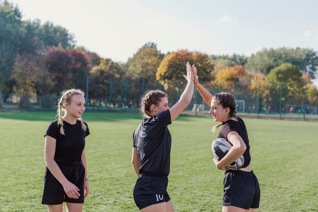 Sportive girls holding soccer ball and high five