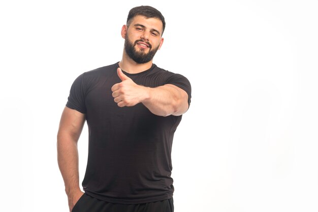 Sportive man in black shirt doing thumb up sign