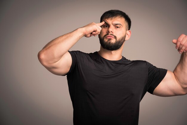 Sportive man in black shirt looks thoughtful. 